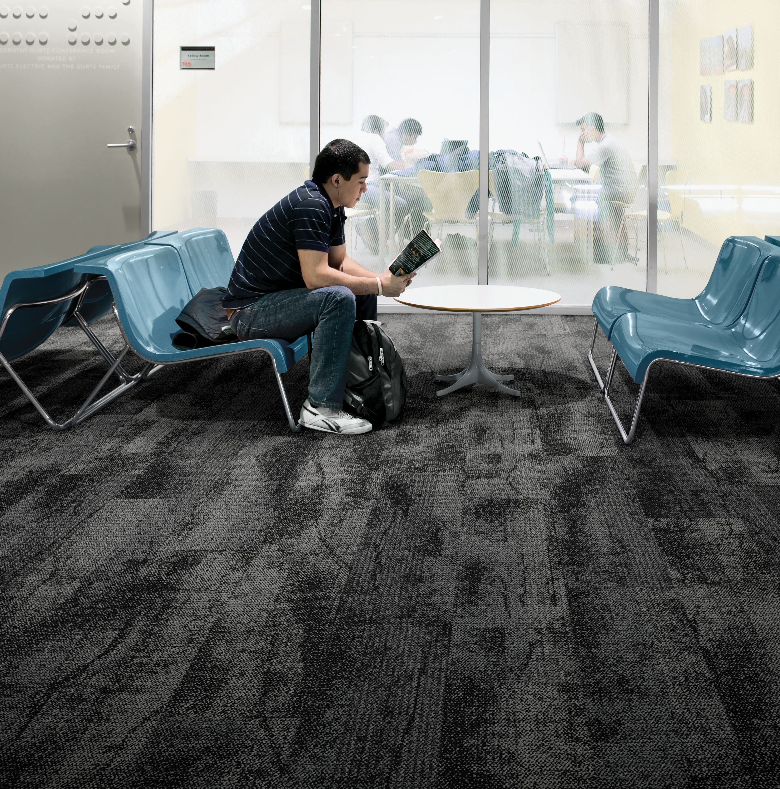 Interface Neighborhood Smooth plank carpet tile in public education space with man reading a book on blue chair imagen número 6